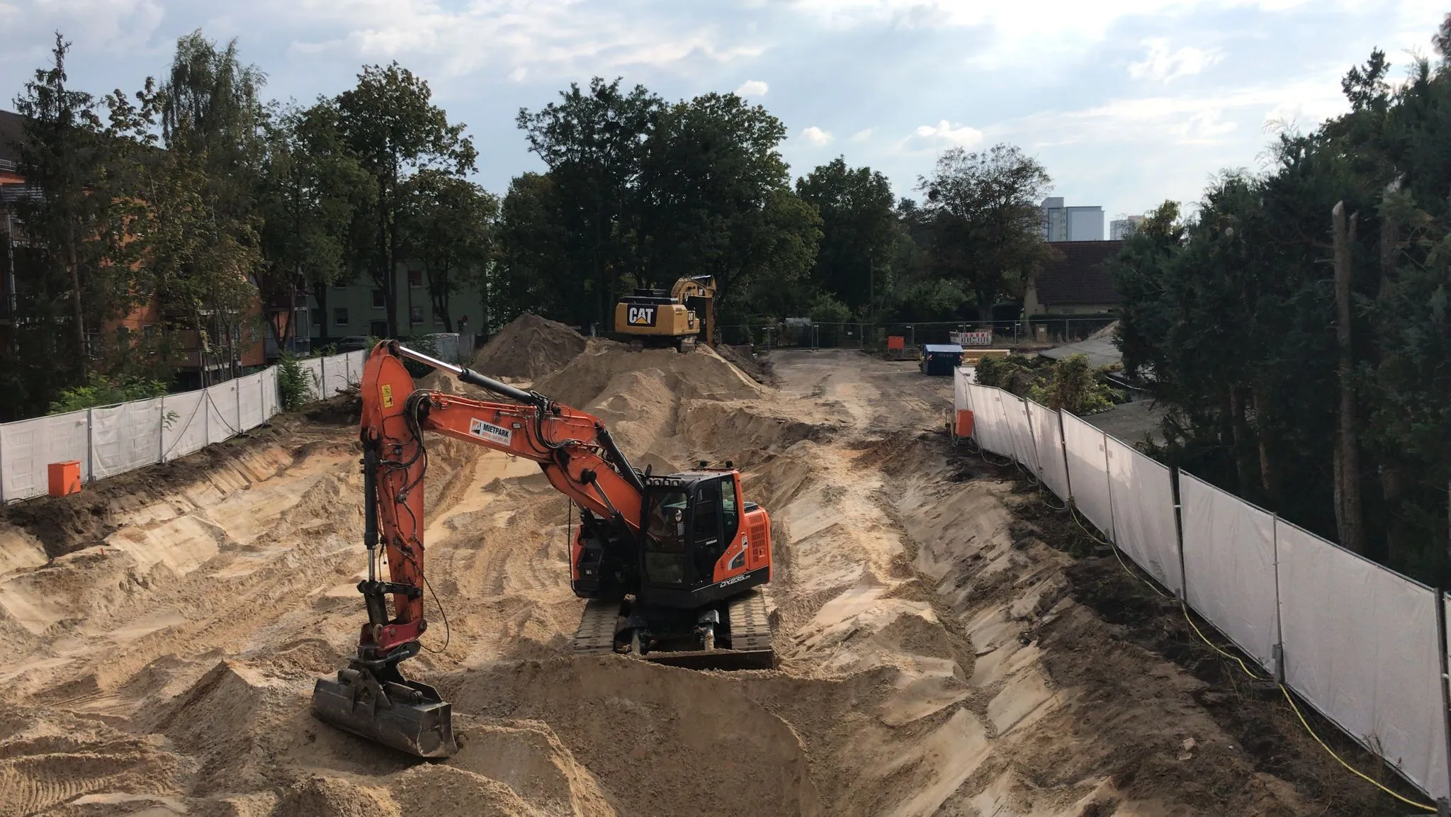 Erdbau-Baugrube der Cavator Bauausführung mit Bagger zwischen Sandwällen
