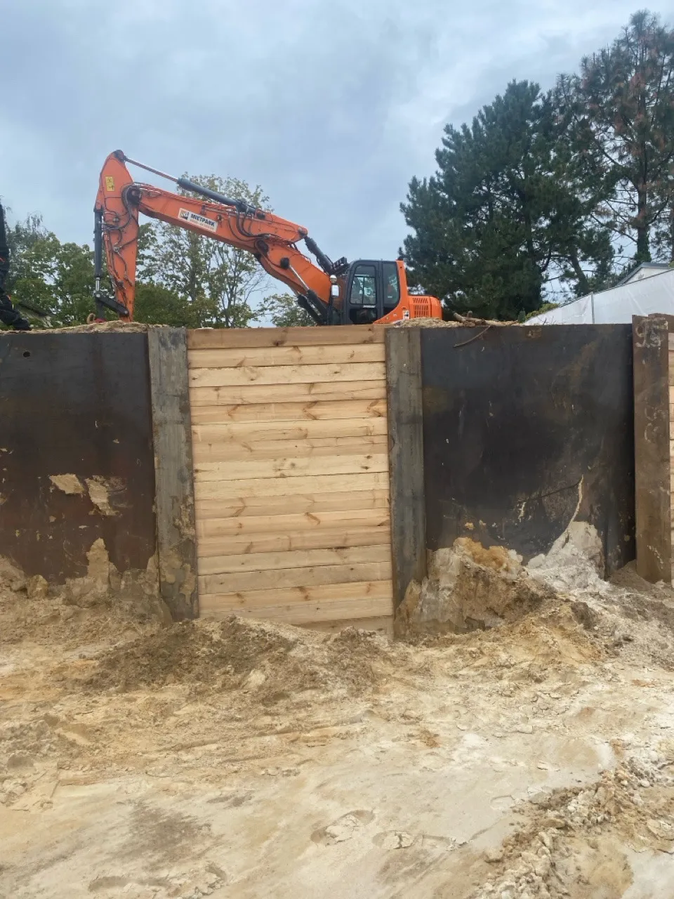 Doosan-Bagger über frisch eingebauten Holzbohlen eines Berliner Verbaus
