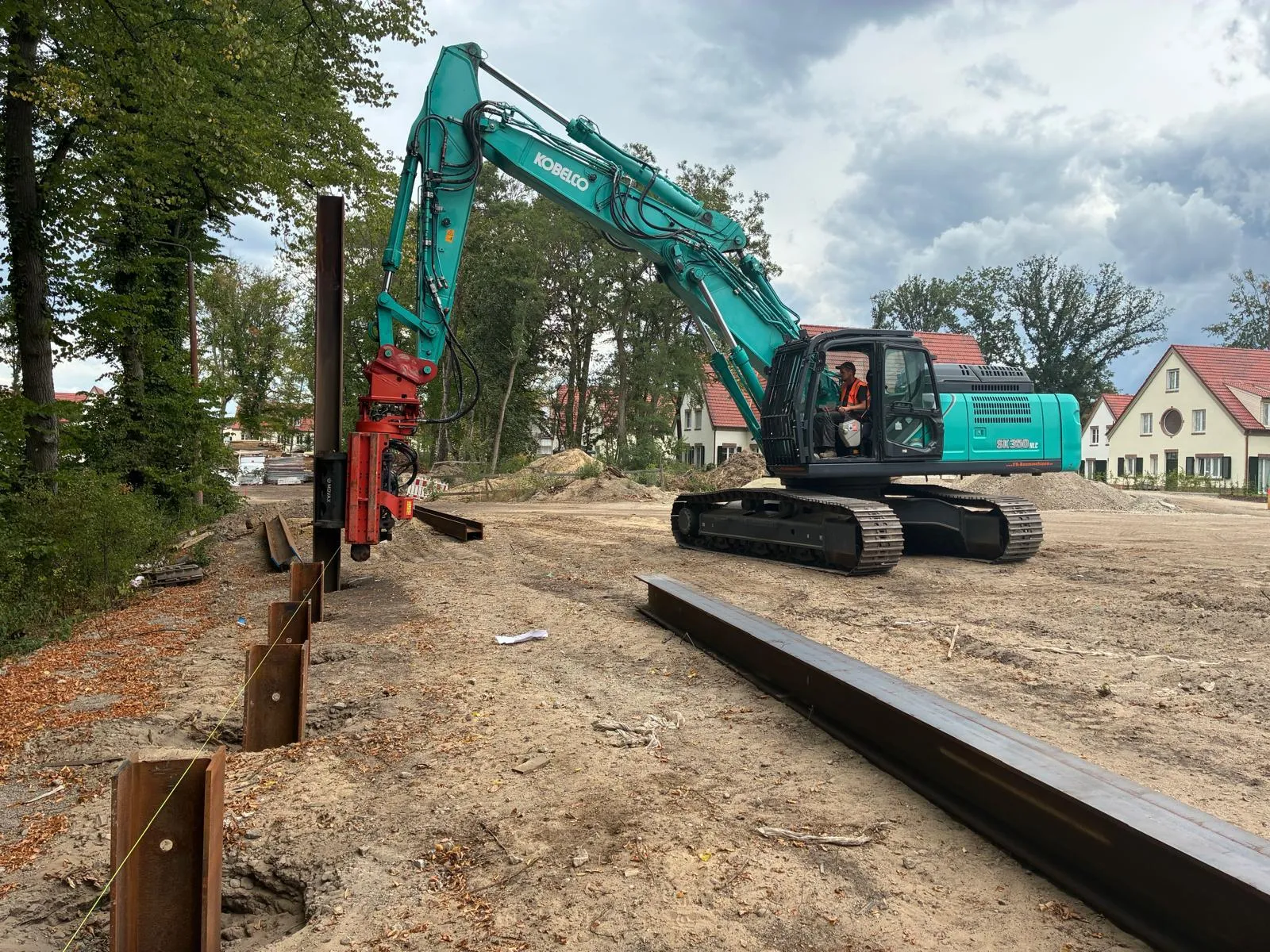 Berliner Ramme: Kobelco-Bagger mit hydraulischem Vibrationsbär rammt Stahlträger einer Trägerbohlwand